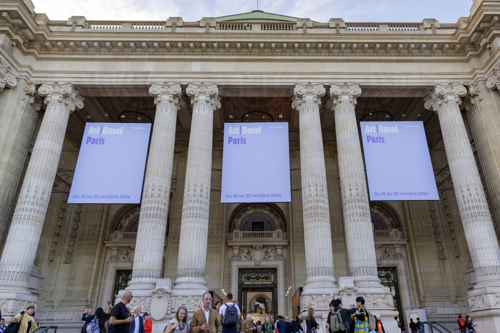 Large banners for "Art Basel Paris" hang between grand Corinthian columns on the facade of a neoclassical building.