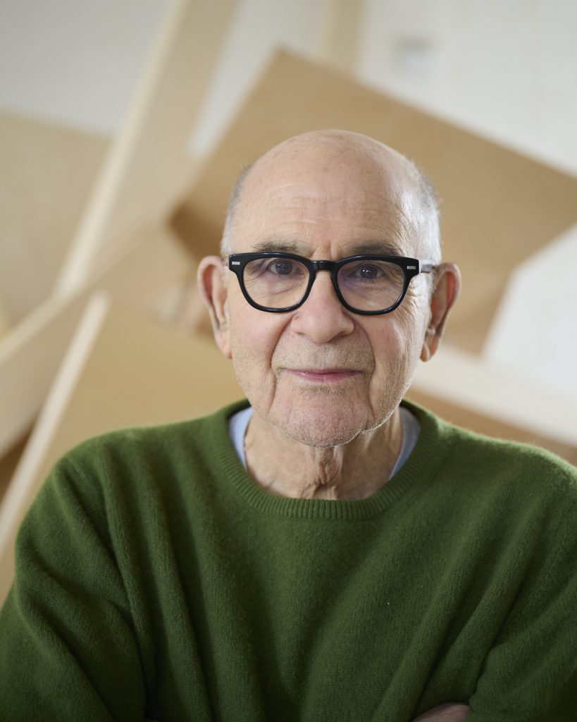 photo of an old, bald man with glasses and green sweater