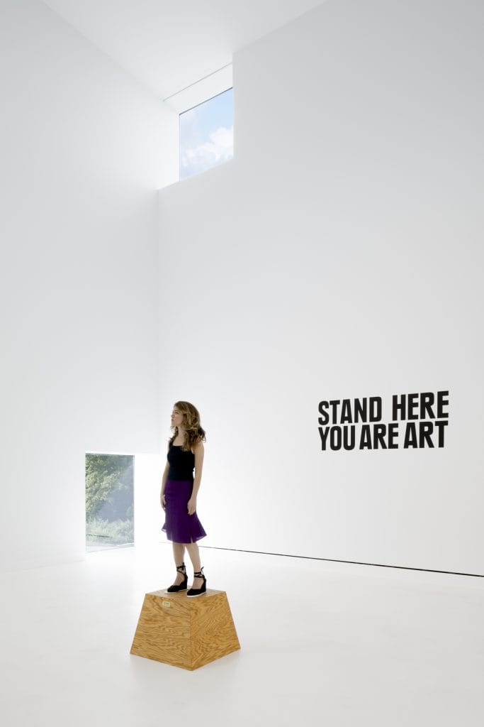 a woman stands on a woman box Manzoni