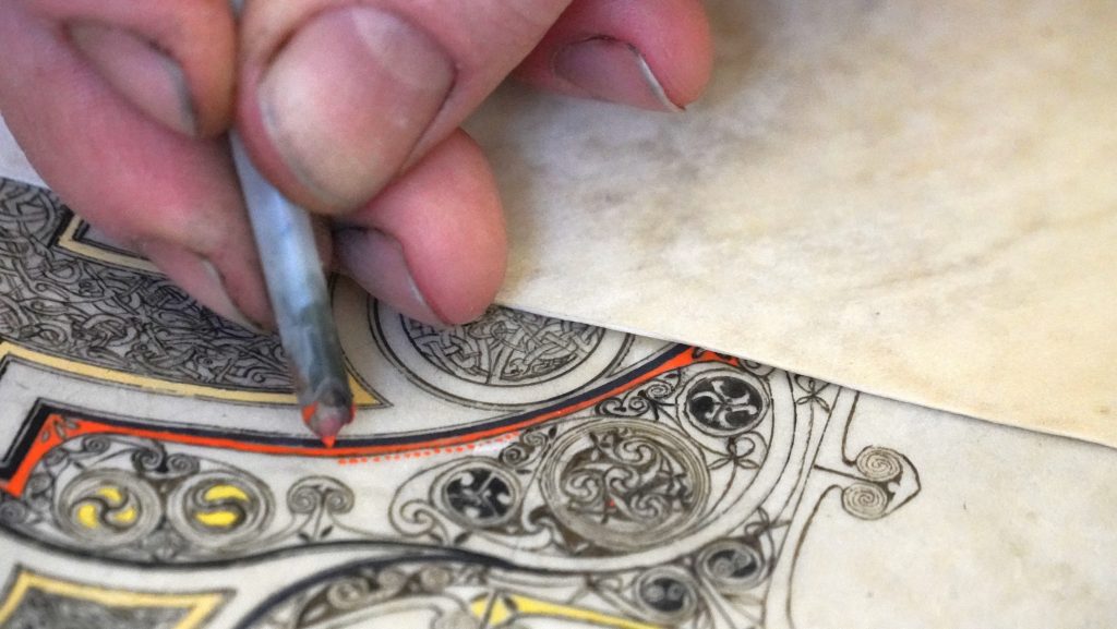 a hand with a pen working on a manuscript