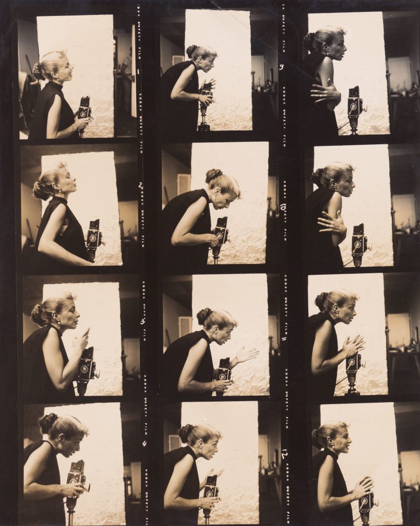 Black-and-white contact sheet showing photographer Lillian Bassman in profile, holding and adjusting a camera while gesturing expressively in a studio setting.