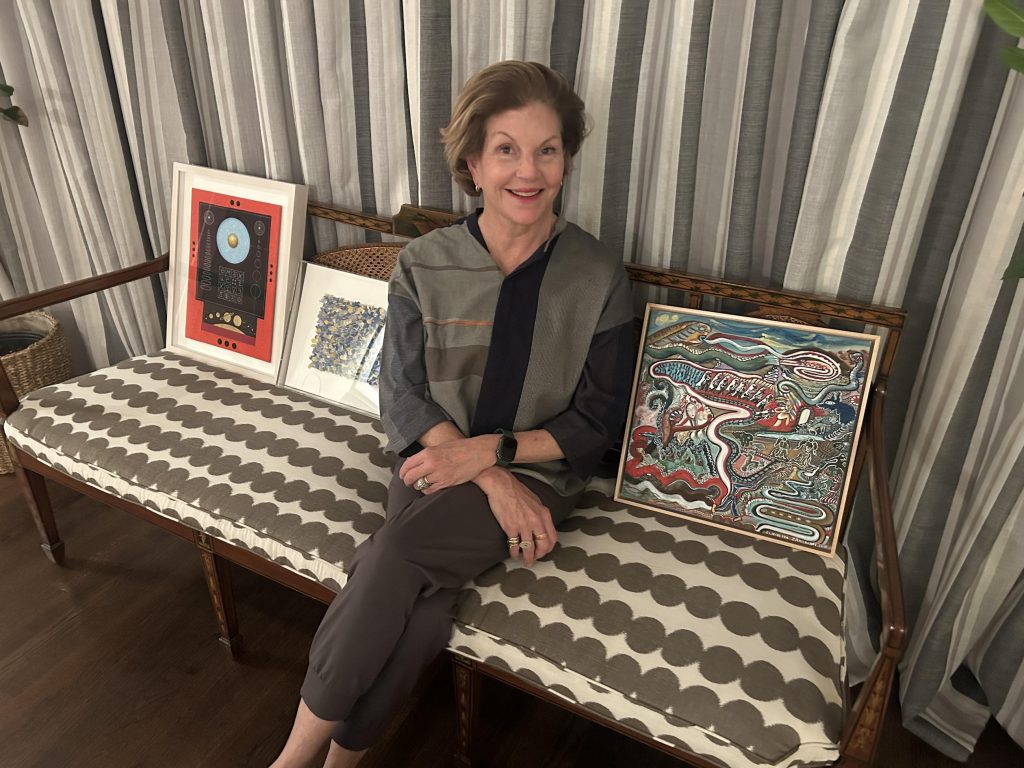 A woman sits on a couch with three small framed artworks around her