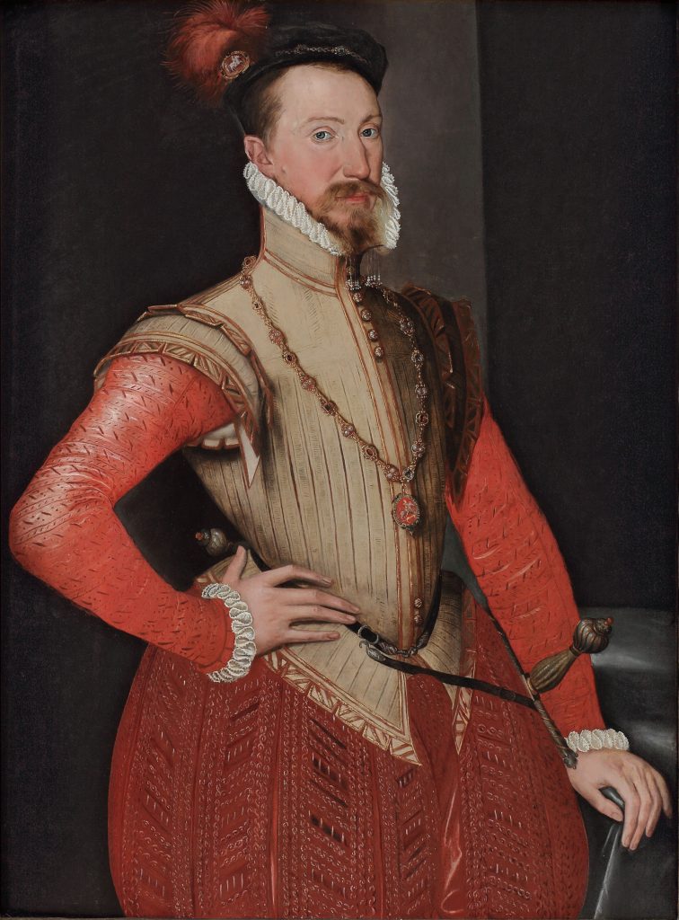 A Tudor portrait of a smartly dressed man which his hand on his hip. He wears loose red trousers
