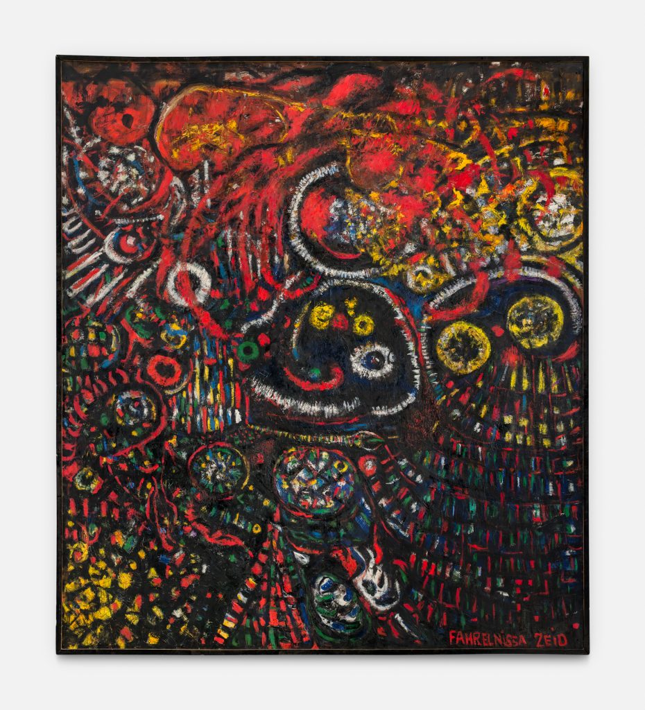 An abstract painting by Fahrelnissa Zeid filled with dense, energetic forms in vivid reds, yellows, whites, and touches of blue and green against a dark background. Swirling lines, circular motifs, and layered patterns interweave across the surface, creating a sense of movement and complexity. The composition features clustered shapes that resemble eyes, wheels, or organic forms, with textured brushwork and splashes of color throughout. The artist’s signature appears in red in the lower right corner.