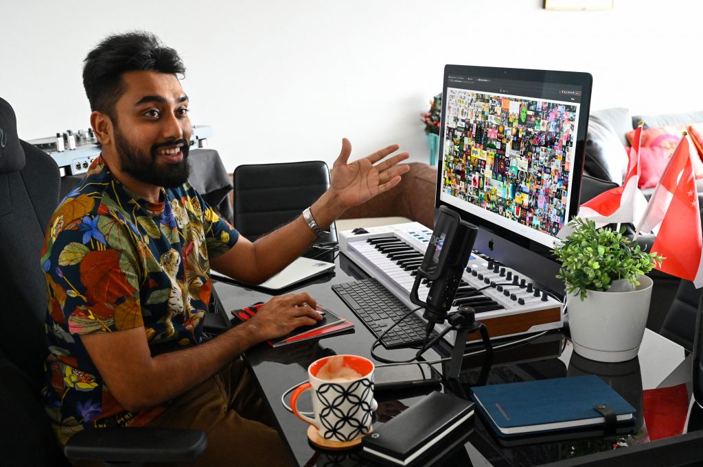 A man sitting at a desk showing off the Beeple NFT, Everydays: The First 5,000 Days, on his computer screen