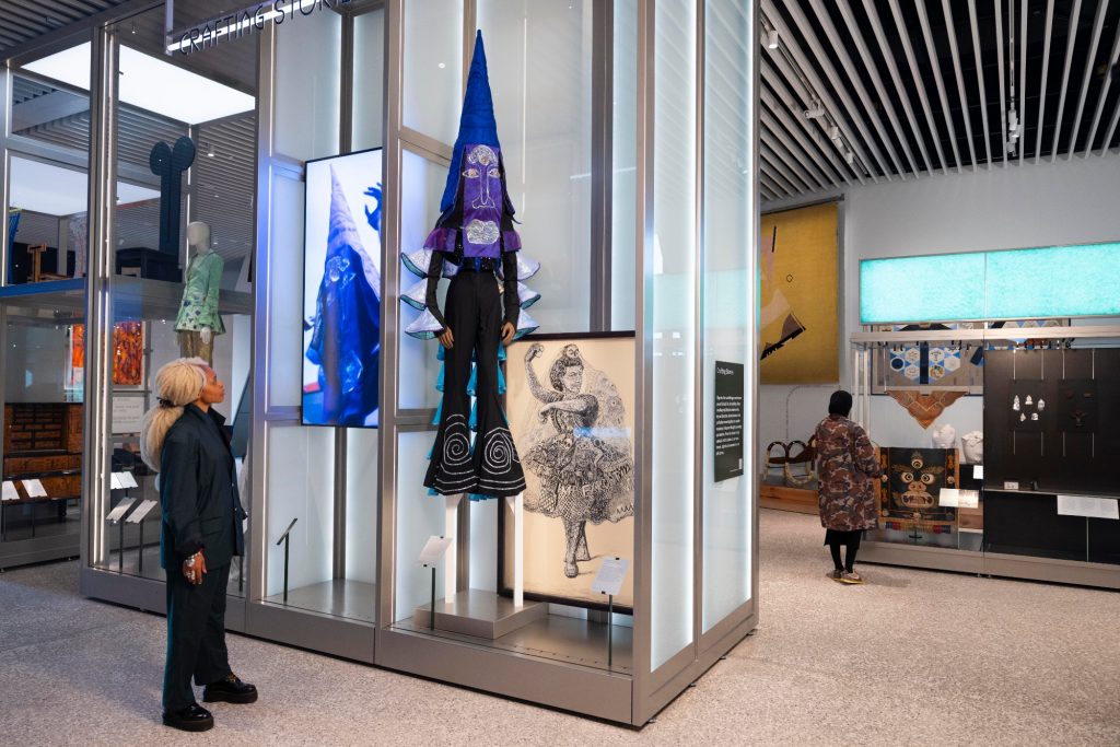 an airy museum space has many exhibits inside glass cases as people mill around