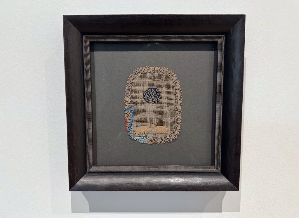 paper drawings by Jasmin Sian are displayed in small, uniform frames on a light blue gallery wall.