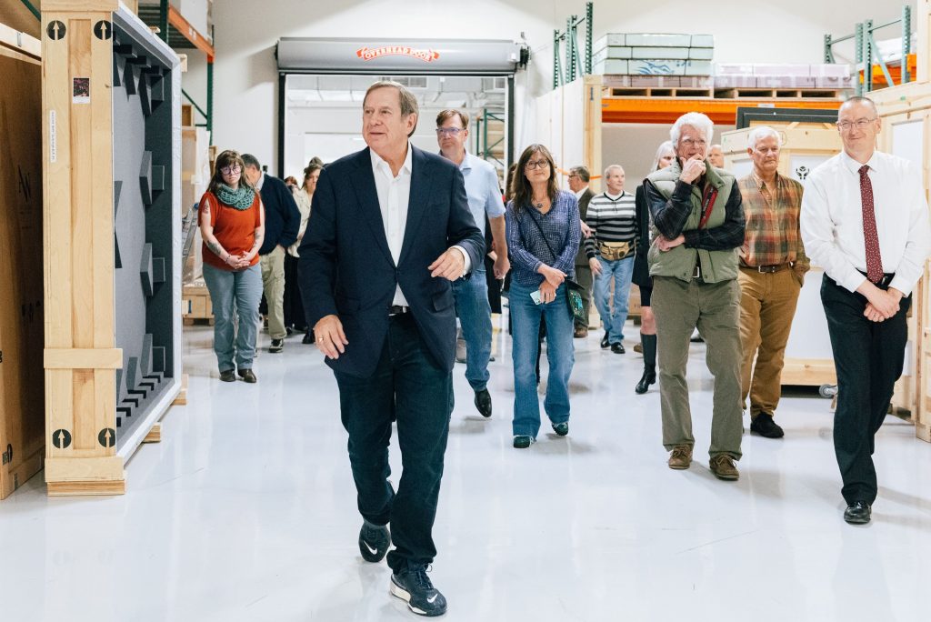 Jordan Schnitzer walks through a warehouse with a group of visitors during a tour of the foundation’s art collection space.