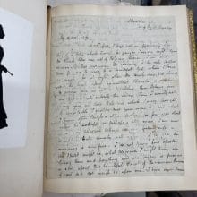 A photograph of a rare book formerly owned by John Hay Whitney opened to a page full of hand written script by Keats