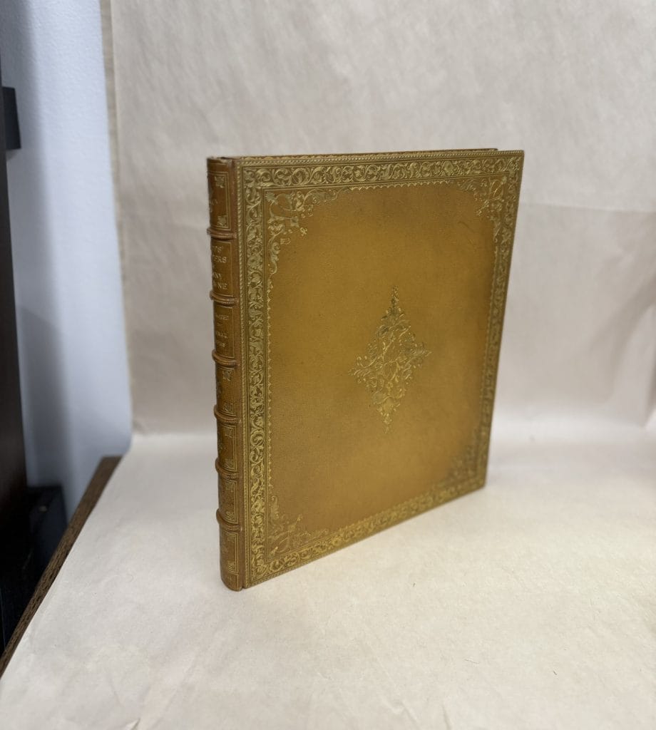A photograph of a once-stolen gilded book standing atop a white table, before a white curtain
