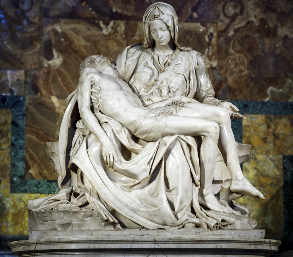 Marble sculpture of Virgin Mary cradling Jesus’ lifeless body, set against a rich marble background.