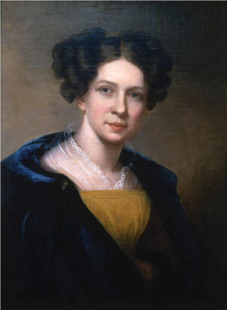 A painting of a young white woman with pale skin and dark brown hair styled in voluminous curls, wearing a dark blue shawl over a gold dress and a delicate lace collar, gazing calmly at the viewer against a soft brown background. It is a Sarah Miriam Peale self portrait. 