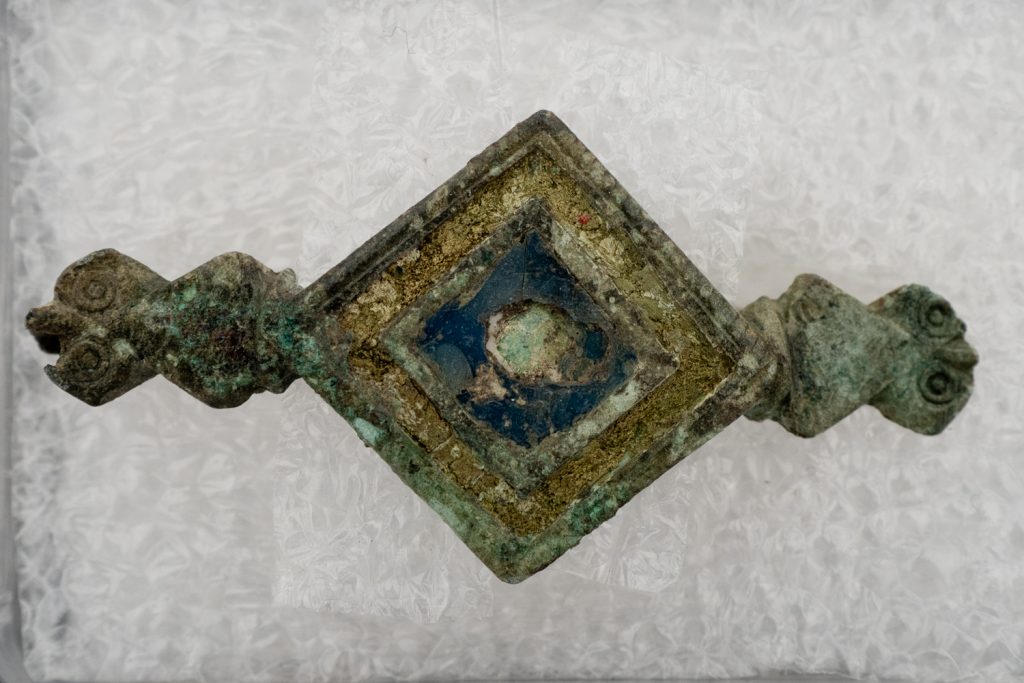 a copper broach on a grey white background