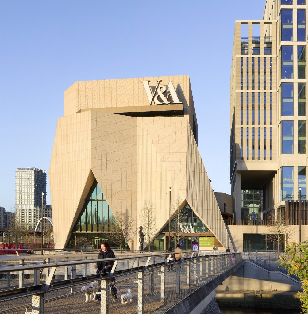 a sand-colored, modernist building rises up in an urban setting, it has 