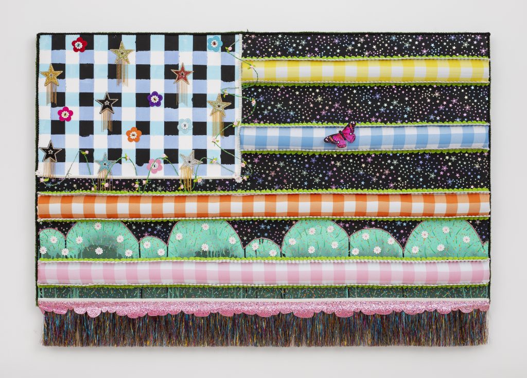 Mixed-media American flag reinterpretation featuring a blue checkered canton with glitter stars and small flowers, black star-patterned stripes, pastel gingham bands, scalloped pink trim, and multicolored fringe along the lower edge.