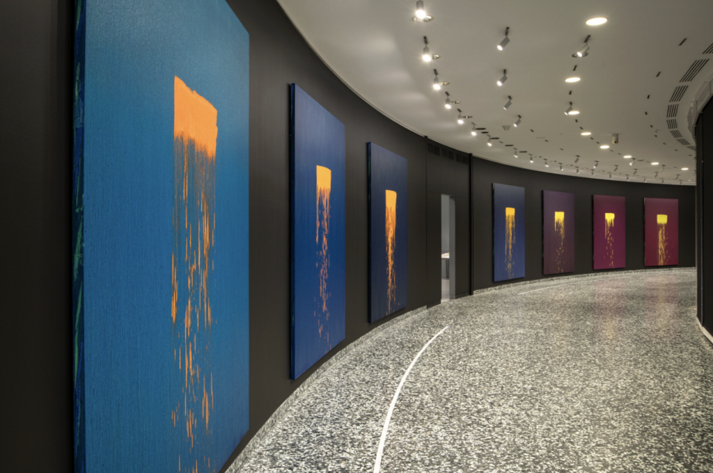 A photograph of a curved room hung with five large-scale Waterfall canvases by Pat Steir, the pioneering artist who recently died