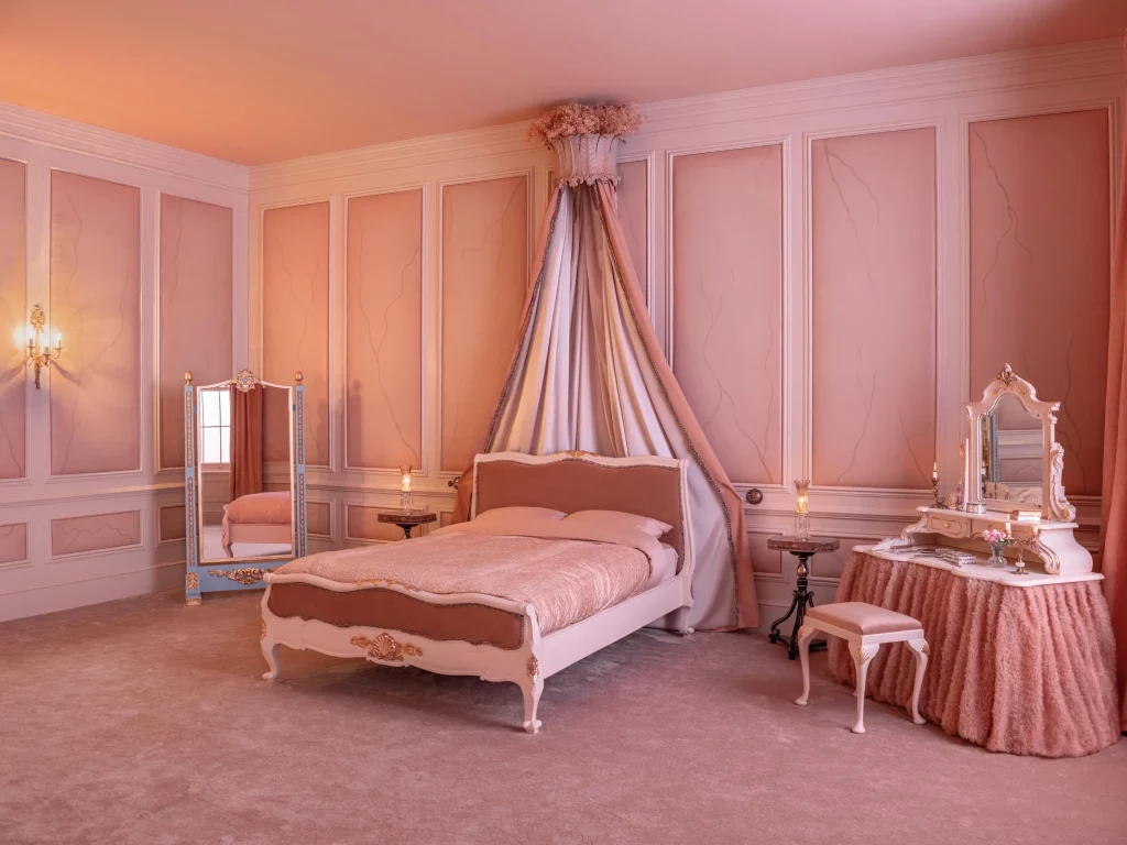 Blush pink bedroom with canopy bed, ornate furniture, paneled walls, and soft romantic lighting throughout, from the Airbnb Wuthering Heights experience..